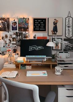 a desk with a computer, keyboard and pictures on the wall in front of it