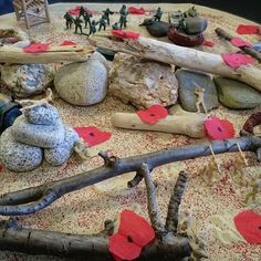 there are many rocks and small figurines on the table with red paper hearts