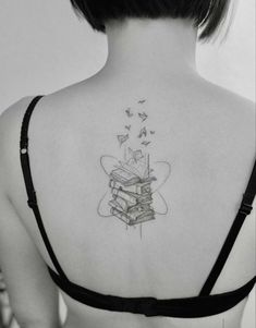 the back of a woman's shoulder with books and butterflies flying around her neck