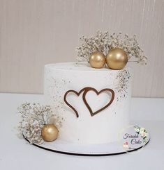 there is a white cake with gold decorations on the top and two golden balls in the middle