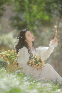 a woman sitting in the grass holding a flower