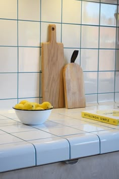 a bowl of lemons sits on the counter next to a cutting board