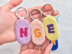 three crocheted keychains with letters on them