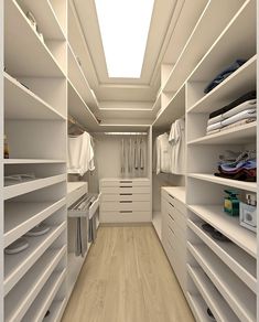 a walk in closet with white shelves and drawers