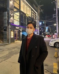 a man wearing a face mask standing on the side of an empty street at night