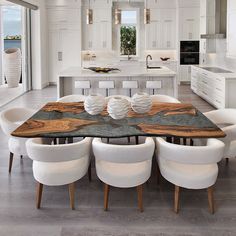 a dining room table with white chairs around it and an island in the back ground