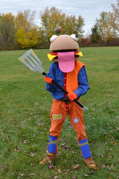 a person in an orange and blue costume holding a pitchfork