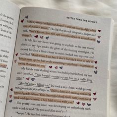 an open book with some writing on the pages and hearts in it's center