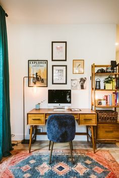 a desk with a computer on top of it in front of a book shelf and bookshelf