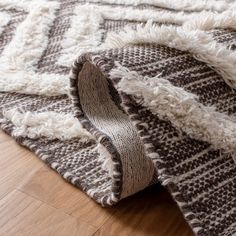 an area rug with white and brown patterns on top of wooden flooring next to a wood floor