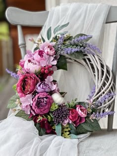 a wreath is sitting on top of a chair with purple flowers and greenery around it