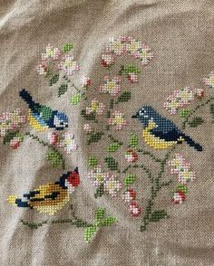 a close up of a piece of cloth with birds on it and flowers in the background