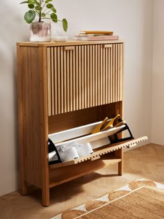 a wooden cabinet with shoes on it and a potted plant