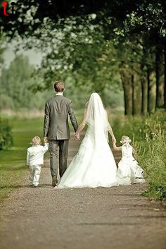 the bride and groom are walking down the path with their two little children in tow