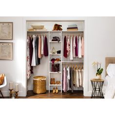 an open closet with clothes and shoes hanging on the shelves, next to a bed