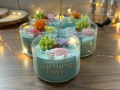 sea turtle cove candles are sitting on a table with fairy lights in the back ground