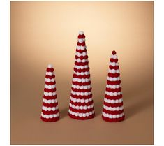 three red and white knitted christmas trees in the shape of santa's hats