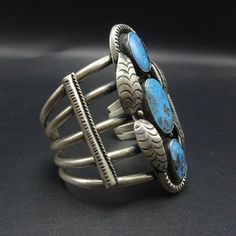 "VINTAGE NAVAJO BRACELET DESCRIPTION: This cuff features three exquisite specimens of high blue Kingman Birdseye turquoise. The gemstones are secure in smooth bezel, on a foundation of heavy gauge vintage sterling silver. Applied leaves and chisel-stamped designs enhance the face of the cuff. This extraordinary bracelet will be a cherished addition to your collection of fine vintage Native American jewelry. MEASUREMENTS: Interior of the cuff measures 5 1/4\" with an additional 1 1/2\" slightly a Southwestern Style Blue Bangle Bracelets, Southwestern Style Blue Bangle Bracelet, Southwestern Blue Cuff Jewelry, Unique Blue Cuff Bracelets, Blue Collectible Cuff Bracelet Bangle, Blue Cuff Bracelets, Vintage Blue Cuff Jewelry, Unique Blue Bangle Jewelry, Blue Cuff Bracelet