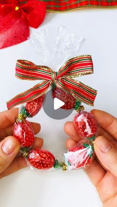 two hands holding candy wrapped strawberries in cellophane and tied with ribbon around them