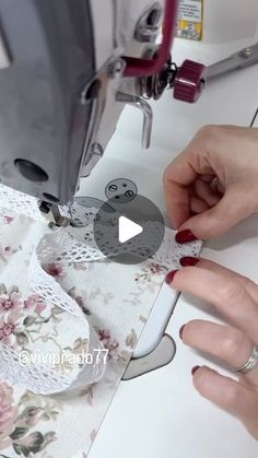 two hands are using a sewing machine to sew on the table cloth with lace