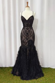 a black evening gown with feathers on the bottom, and an open - back design