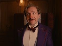 a man wearing a purple suit and bow tie