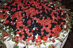 the cake is decorated with berries and leaves