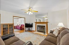 a living room filled with furniture and a fire place in front of a tv mounted on a wall