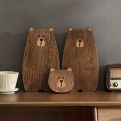 two wooden bears sitting on top of a table next to a cup and toaster