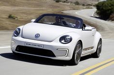 a white vw beetle cab driving down a road with hills in the back ground