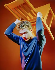 a young man holding up a wooden chair over his head