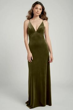 a woman wearing a green velvet gown with spaghetti straps and open back, standing in front of