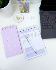 a laptop computer sitting on top of a desk next to a notepad and pen