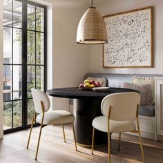 a dining room table with two chairs and an art piece on the wall above it