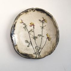 a white plate with yellow flowers painted on the inside of it, sitting on a table