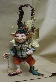 a small figurine is dressed as a fairy with gold leaves on her head