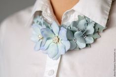 a close up of a person wearing a white shirt with blue flowers on the collar