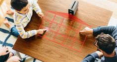 three people sitting at a table with a game on the floor in front of them