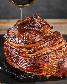 a large piece of meat is being drizzled with sauce