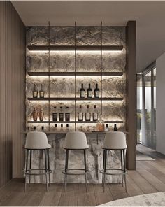 a bar with three stools in front of it and several bottles on the wall