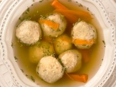 a white bowl filled with dumplings and carrots on top of a cloth covered table