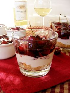 cherries and yogurt are served in small bowls on a red tablecloth