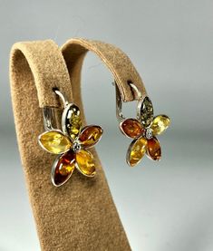 Valentines Day Perfect Gift!Add a touch of natural elegance to your jewelry collection with our Multicolour Flower Amber Earrings, set in high-quality 925 Sterling Silver. These stunning earrings are designed for women who appreciate unique, handcrafted jewelry that features the vibrant beauty of amber in a floral design. Key Features: Genuine Multicolour Amber: Each earring showcases a blend of green, yellow, and brown Baltic amber stones, carefully arranged to create a beautiful flower design Baltic Amber Jewelry, Beautiful Flower Designs, Amber Earrings, Amber Stone, Wedding Jewelry Earrings, Amber Jewelry, Stunning Earrings, Baltic Amber, Design Floral