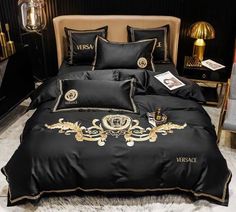 a bed with black and gold comforters on top of white furnishing next to a chair