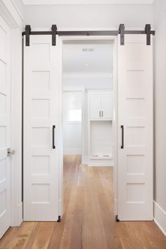 an empty room with white doors and wooden floors