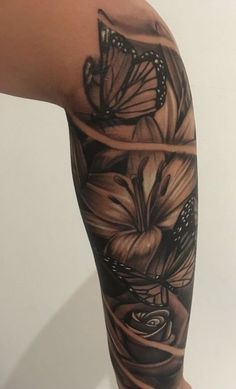 a woman's arm with flowers and butterflies on it, both in black and white