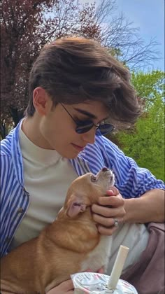 a young man holding a small dog in his lap