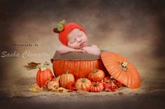 a baby sleeping on top of a pile of pumpkins