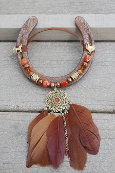 an orange and brown feather is attached to a necklace on a piece of wooden plank