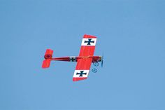 a red and white airplane flying in the sky with two propellers on it's wings